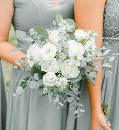 the bridesmaids are holding their bouquets with white flowers and greenery on them