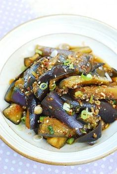 a white plate topped with eggplant covered in sesame seeds and garnish