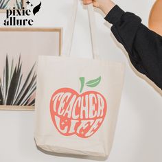 a person holding up a bag with an apple on it and the words teacher's life printed on it