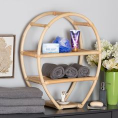 a bamboo shelf with towels, candles and other items on it next to a flower vase