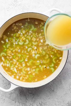 a pot filled with soup next to a glass of orange juice