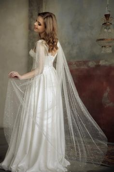 a woman in a white wedding dress with a long veil on her head and shoulders