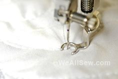 the sewing machine is being used to sew on white fabric with silver tips and thread