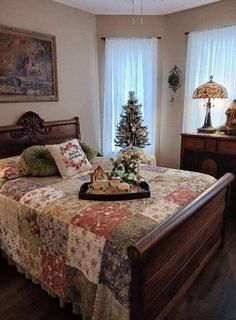 a bed with a christmas tree on top of it in a bedroom next to two windows