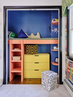 a bedroom with blue walls and colorful furniture in the corner, along with a yellow dresser