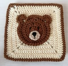 a crocheted square with a brown teddy bear on the front and white background