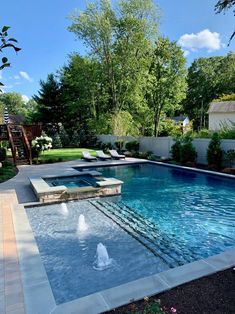 an outdoor swimming pool surrounded by trees and shrubs, with lounge chairs on the side