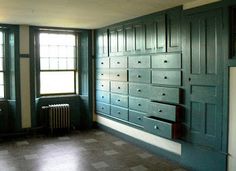 an empty room with many drawers and windows on the wall, in front of a radiator