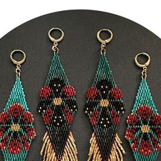 three pieces of beaded art hanging on a black surface with gold accents and red flowers