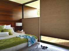 a bedroom with brown shades on the window and green bedding in front of it