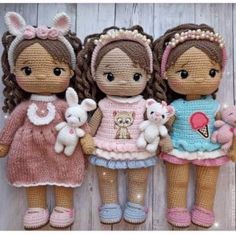 three crocheted dolls standing next to each other on a wooden floor with white boards behind them