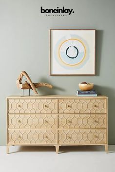 a wooden dresser sitting next to a painting on the wall