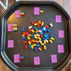 a tray filled with lots of colorful legos on top of a wooden table next to numbers