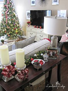 a living room decorated for christmas with candles and decorations on the table in front of it