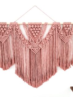 a pink wall hanging with fringes and beads