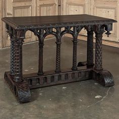 an ornate wooden table sitting in front of some doors