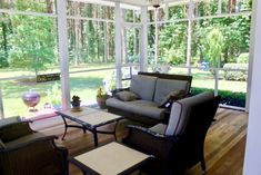 a living room with couches and chairs in front of large glass windows that look out onto the woods