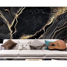 a couch with a guitar on it in front of a black and gold wall mural