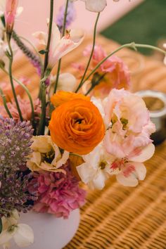 a vase filled with flowers sitting on top of a table next to an empty cup