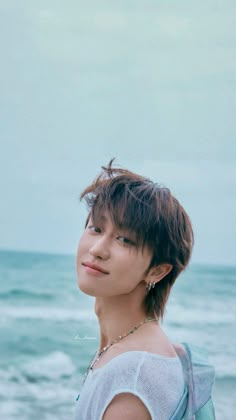 a person standing on top of a beach next to the ocean and looking off into the distance