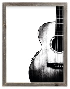 a black and white photo of an acoustic guitar in a wooden frame on a wall