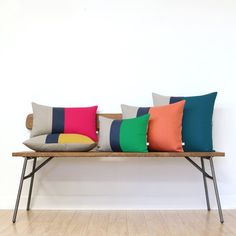 a wooden bench topped with lots of colorful pillows