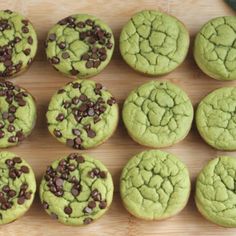 green cookies with chocolate chips sitting on a cooling rack next to a person's hand