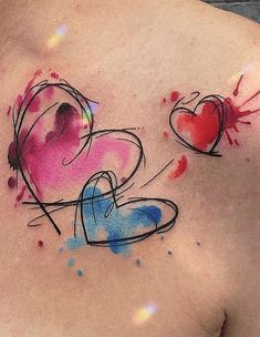 a woman's chest with two hearts painted on it and watercolor splashes