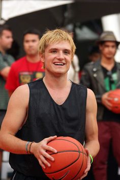 a young man holding a basketball while standing next to other men in front of him