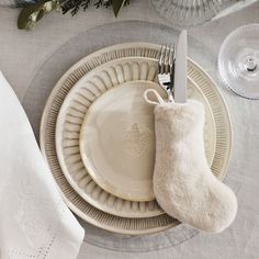 a white plate topped with a christmas stocking next to a wine glass and silverware