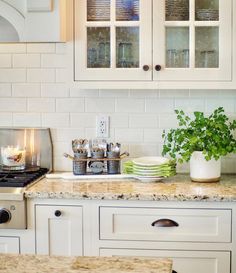 a kitchen with white cabinets and marble counter tops