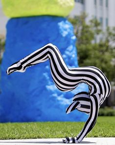 a fake zebra standing on its hind legs in front of a blue and green sculpture