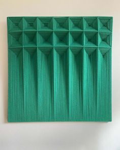 a piece of art that is made out of green paper with squares and lines on it