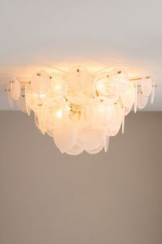 a white chandelier hanging from the ceiling in a room with beige walls and flooring