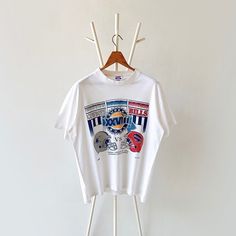 a white t - shirt hanging on a clothes rack