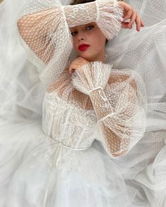 a woman wearing a white dress and veil with her hands on her head, posing for the camera