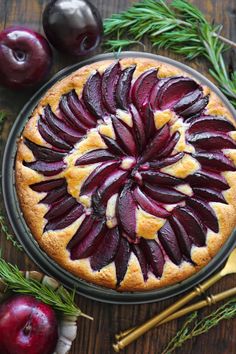 a pie topped with sliced beets on top of a wooden table next to fruit