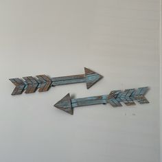 two metal arrows pointing in opposite directions against a white wall with blue paint on it