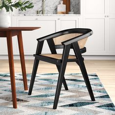 a black chair sitting on top of a rug next to a wooden table and chairs