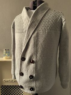 a white sweater with black buttons on it