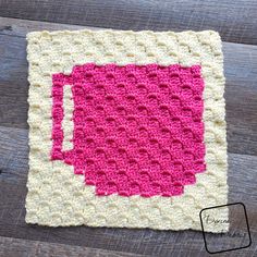 a pink and white crocheted square on top of a wooden table with the words,