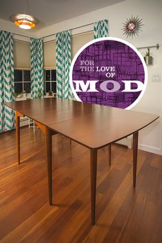 a large wooden table sitting on top of a hard wood floored floor next to a window