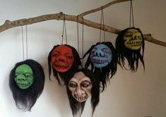 three masks hanging from a tree branch with long black hair and two skulls on them