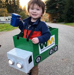 a young boy is dressed up as a toy truck and holding a cup in his hand