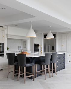 a large kitchen with an island and bar stools in the center, surrounded by white cabinets