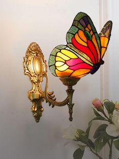 a lamp that is on the side of a wall next to a vase with flowers