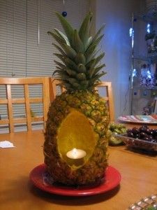 a pineapple sitting on top of a red plate with a lit candle in it