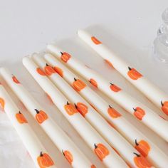 several white candles with orange pumpkins on them