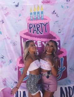 two beautiful women standing next to each other in front of a birthday cake sign with candles on it