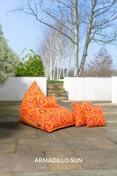 an orange bean bag sitting on top of a stone floor next to a white wall